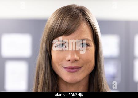 Confident female teacher smiling in classroom, engaging with students in school environment Stock Photo