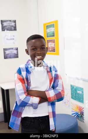 Smiling african american boy in colorful shirt standing confidently in classroom at school Stock Photo