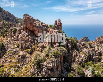 A dramatic rock formation with a heart shaped hole at the Calanches de Piana, a UNESCO heritage site on the west coast of the Mediterranean island of Stock Photo