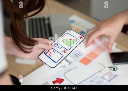 Mobile App Design. User interface mockup displayed on smartphone during collaborative session. Stock Photo