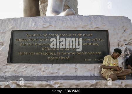 Young man sitting at the foot of the Amazon monument in Cotonou, Benin Stock Photo