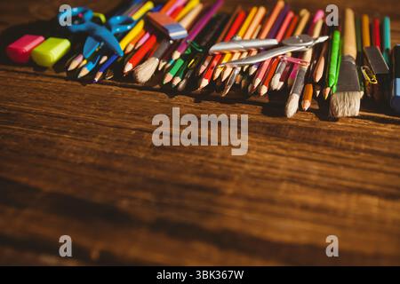 Flat design is showing pencils, brushes, markers lined along top edge on wooden table, copy space Stock Photo