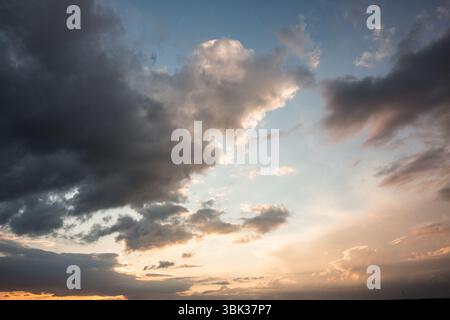 Storm clouds are glowing with sunset rays above wispy clouds near horizon in flat illustration Stock Photo