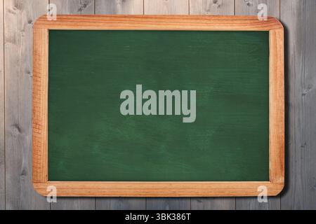 Flat design is showing green chalkboard with light wood frame on grey wood-paneled wall, copy space Stock Photo