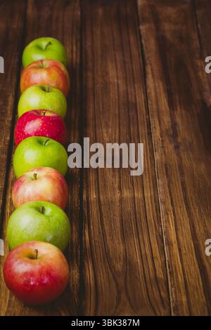Displaying vertical alternating green and red apples on dark wooden plank surface in flat design Stock Photo