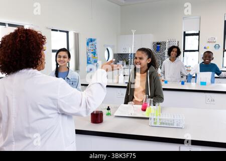 In school laboratory, female teacher engaging diverse students in science experiment Stock Photo