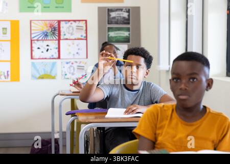 In classroom, focused boy holding pencil, listening attentively during lesson, at school Stock Photo