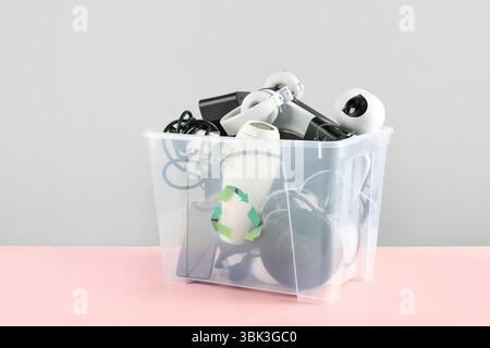 Recycle bin with different household appliances on pink background Stock Photo