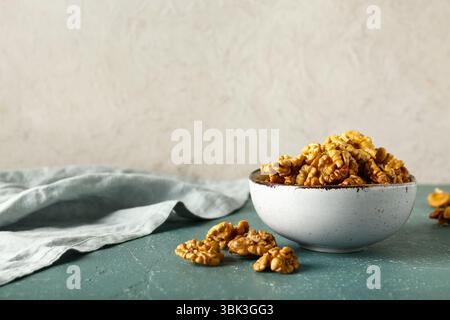 Bowl of tasty walnuts on table against white wall Stock Photo