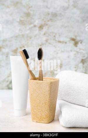 Holder with bamboo toothbrushes, clean towels and paste on light background Stock Photo