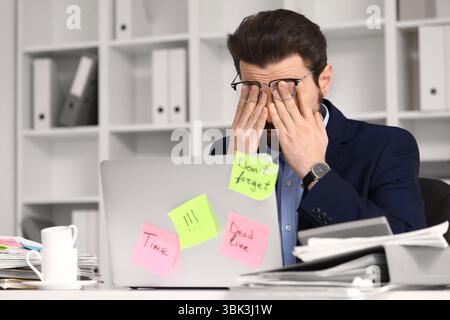 Stressed businessman with a lot of work trying to meet deadline in office Stock Photo