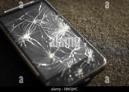 Smartphone with broken screen on dark background Stock Photo