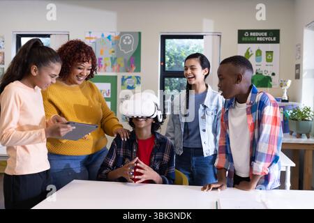 In school, diverse students using virtual reality, smiling and interacting in classroom Stock Photo