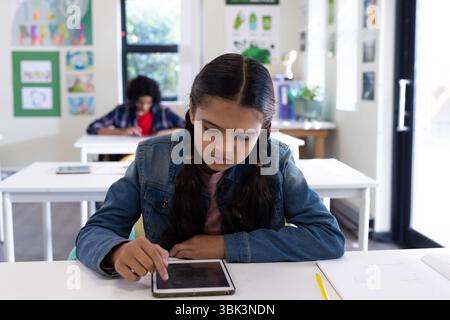 In school, girl using tablet in classroom, focusing on digital learning Stock Photo