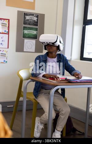 Girl using VR headset in classroom, exploring virtual learning experience, at school Stock Photo
