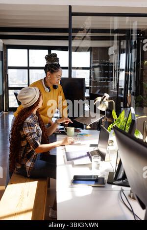 Collaborating on coding project, diverse women focused in modern office Stock Photo