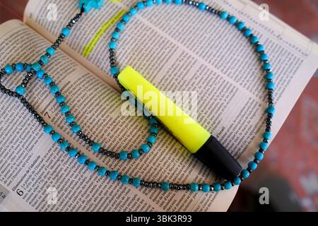 Bible with a blue rosary and a yellow highlighter. Stock Photo