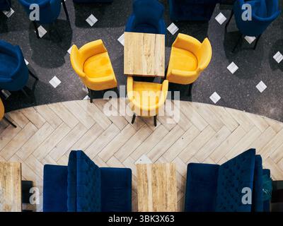 Restaurant with a checkered floor and blue and yellow chairs. The chairs are arranged in a way that they face the table Stock Photo