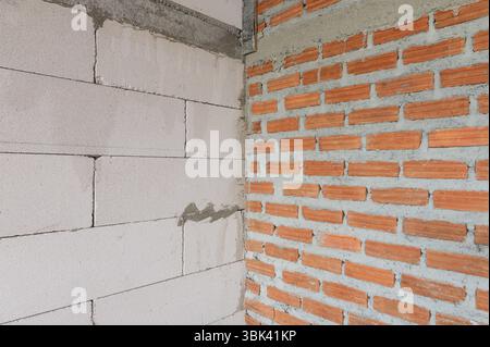 Two different construction wall materials lightweight concrete blocks and red bricks Stock Photo