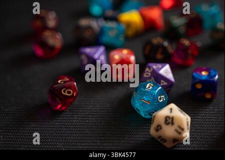 A close-up of a colorful collection of polyhedral dice for tabletop RPGs. The sharp focus is on a vibrant, translucent blue die Stock Photo