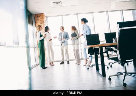 A professional team collaborates in a modern office setting to discuss a dynamic group project with diverse perspectives. Stock Photo