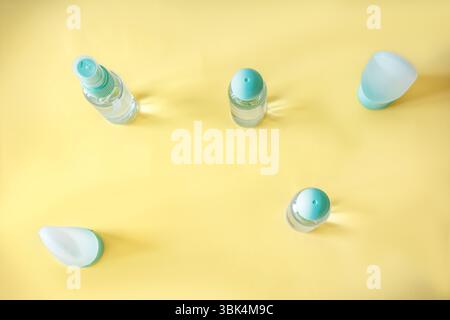 Flat lay of assorted travel-size cosmetic containers with turquoise lids on a smooth yellow backdrop. Clean, organized layout for skincare, toiletries Stock Photo