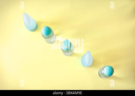 Symmetrical composition of plastic cosmetic bottles and travel toiletry containers on a pastel yellow background. Simple, fresh beauty product layout Stock Photo