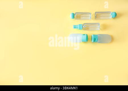 Top view of plastic travel bottles arranged in rows on bright yellow background. Clean, minimalist layout ideal for cosmetic packaging, beauty blogs o Stock Photo