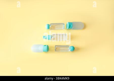 Neatly aligned flat lay of transparent and silicone travel bottles on pastel yellow background. Clean composition with repetition and balance, ideal f Stock Photo