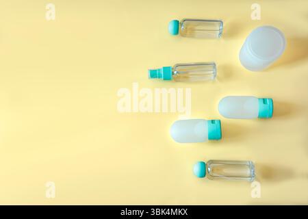 Top view of assorted travel containers and one large round jar for cosmetics or creams, all on a clean yellow background. Perfect for skincare, wellne Stock Photo