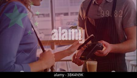 Tapping smartphone customer in blue top paying with handheld terminal at wooden counter with latte Stock Photo