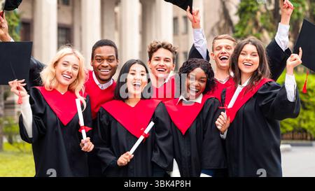 Joyful multiethnic students with diplomas celebrating graduation Stock Photo