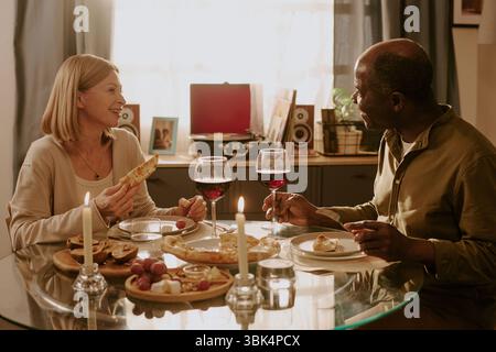 Senior Caucasian Woman and Senior Black Man Sharing Pizza and Laughing Together Stock Photo