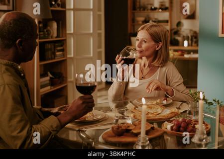 Senior Multiethnic Couple Enjoying Drinking Red Wine Together Stock Photo