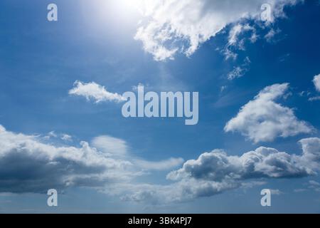 Large cumulus clouds are floating across flat design sky with sunlit highlights and wispy streaks Stock Photo