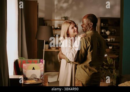 Senior Caucasian Woman and Senior Black Man Dancing Together and Smiling Indoors Stock Photo