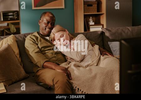 Senior Interracial Couple Relaxing Together on Sofa and Enjoying Romantic Moment Stock Photo