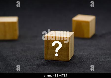 Three wooden cubes with question marks aligned in a row Stock Photo