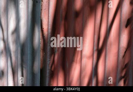 dark shadows on red painted corrugated metal wall Stock Photo