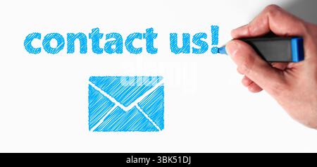 Website contacts concept with a man hand drawing a blue contact us sign and an email icon on white background. Stock Photo