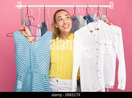Young woman holding hangers with dress and shirt Stock Photo