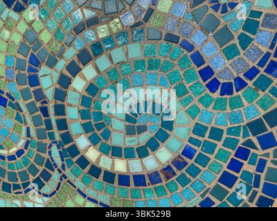 A vibrant close-up of a swirling mosaic pattern composed of blue, teal, green, and turquoise ceramic tiles. This abstract, geometric background Stock Photo