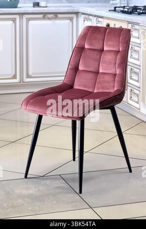 Soft comfortable red modern chair, over out of focus interior kitchen background Stock Photo