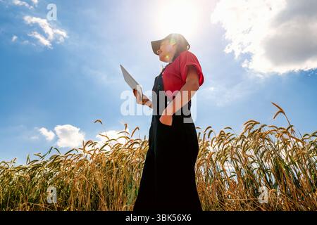 Low angle view of modern female farmer using digital tablet in cereal field Stock Photo
