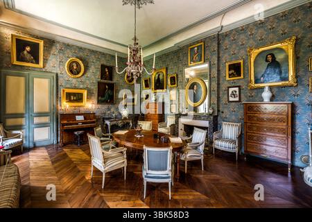 Salon in George Sand's house in Nohant with portraits of her ancestors and descendants. The Nohant estate is still inextricably linked to George Sand and furnished with many original pieces. Above the fireplace hangs the famous portrait of George Sand by Auguste Charpentier from 1838. Place Sainte Anne, Nohant-Vic, Centre-Val de Loire, France Stock Photo