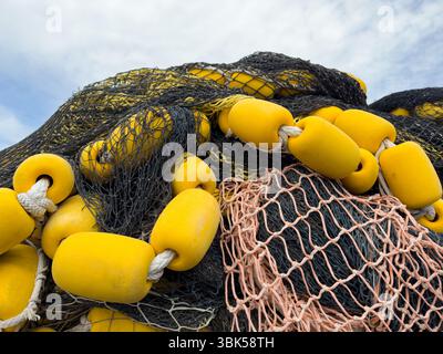 High pile of industrial fishing nets with yellow floats on rope Stock Photo