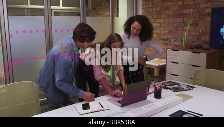 Group of three colleagues collaborating in office meeting area, analyzing charts on laptop Stock Photo