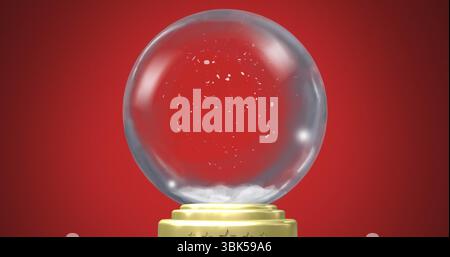 Glinting glass snow globe displaying swirling artificial snow flakes in studio, with gold base Stock Photo