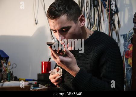 A master technician performing screen gluing on a phone, using specialized electronics tools and wipes. Expert screen gluing in action Stock Photo