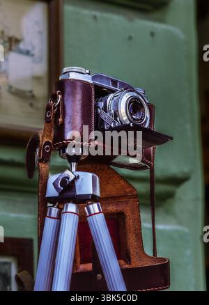 A vintage camera, beautifully preserved in its leather case and mounted on a classic tripod, stands ready to capture timeless moments. Stock Photo